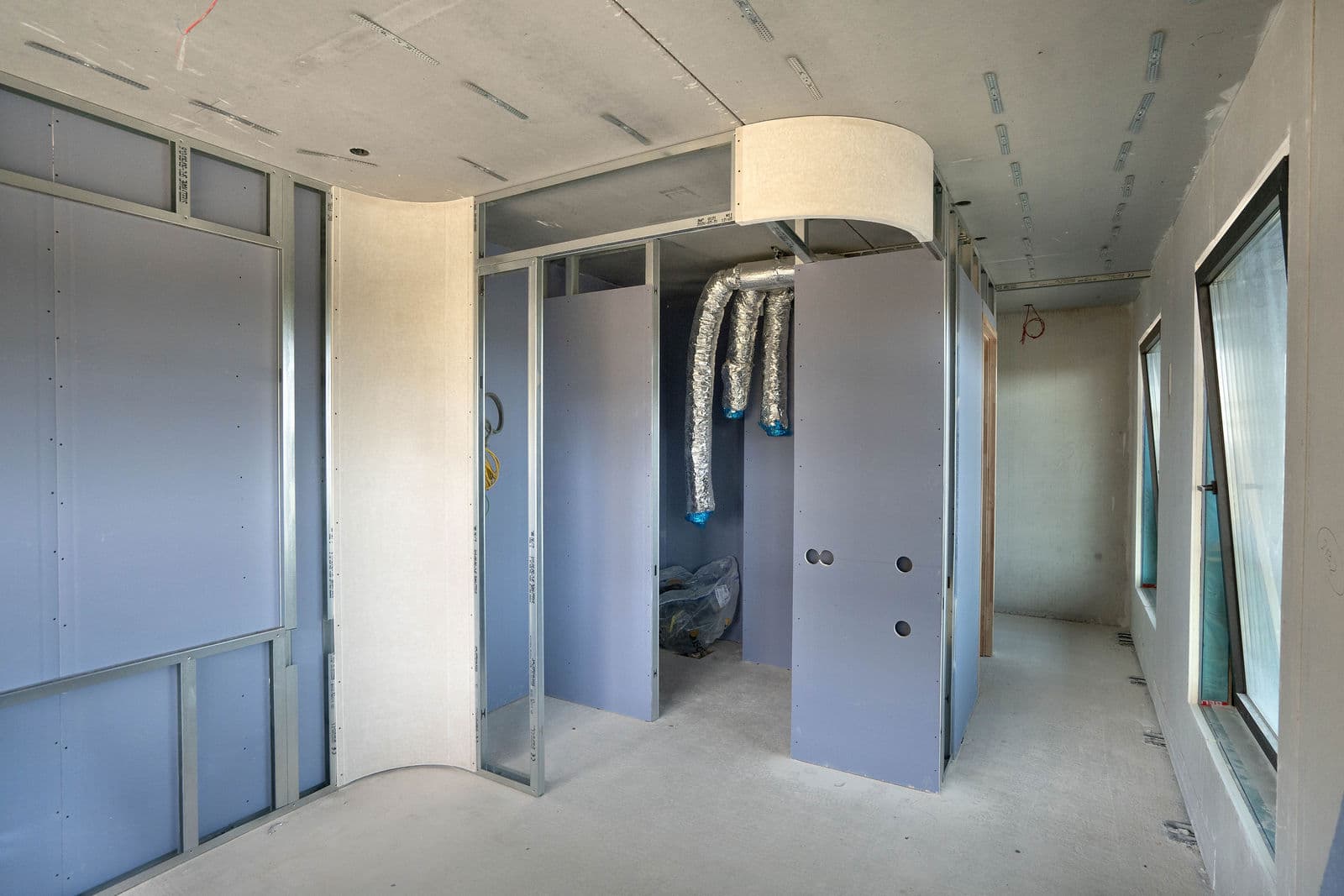 Ruimte in afbouw met metal-studwanden en een gebogen plafond